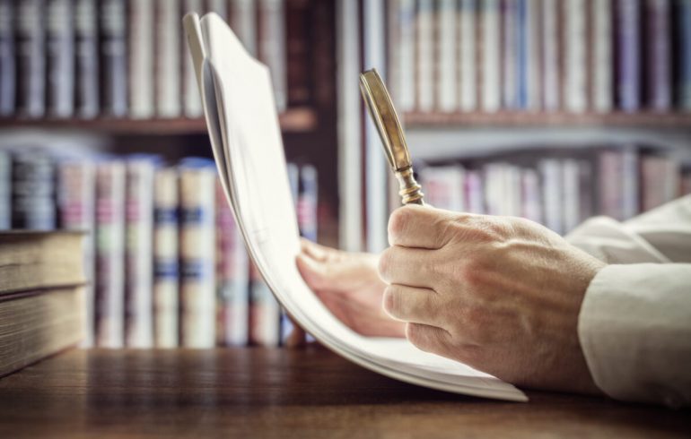 Businessman reading documents with magnifying glass concept for analyzing a finance agreement or legal contract